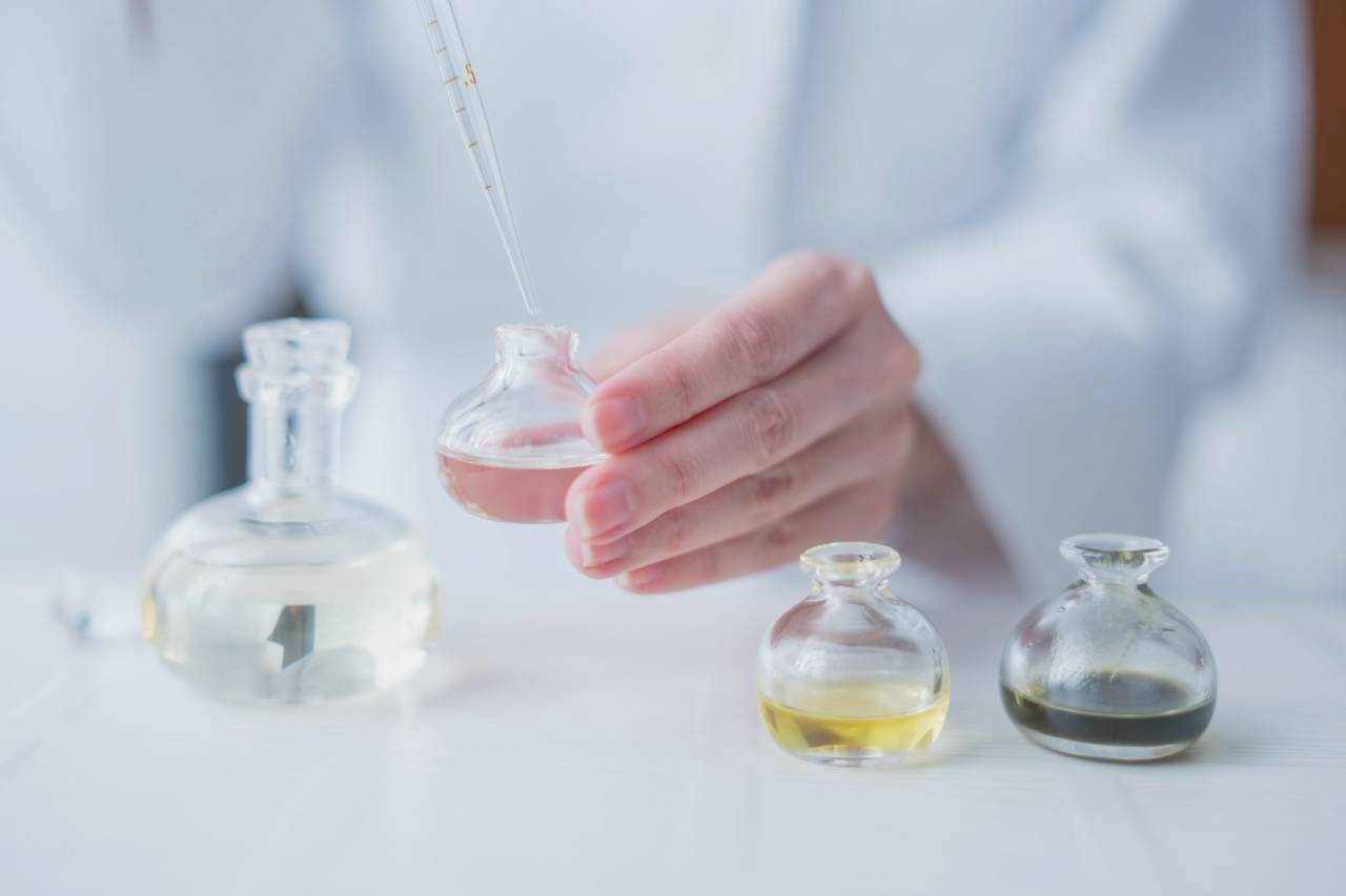 石鹸のつくり手が、色の異なるオイルを手に取る様子
